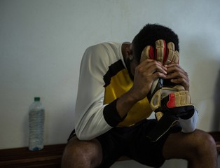 Wall Mural - Football player sitting on bench in changing room