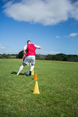 Wall Mural - Soccer player dribbling through cones