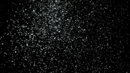 Wall Mural - snowfall bokeh lights on black background, shot of flying snowflakes in the air