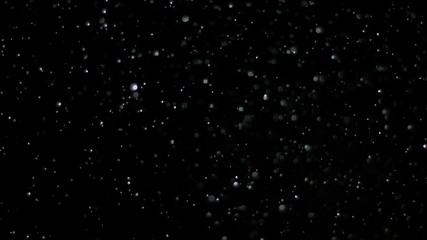 Wall Mural - snowfall bokeh lights on black background, shot of flying snowflakes in the air