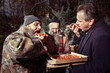 Manager man in park eating christmas pizza with homeless men