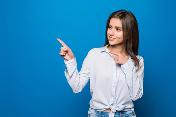 Smiling business woman pointing finger at copy space. Blue wall.