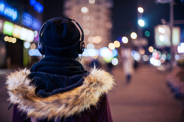 Wall Mural - Girl walking through night city street  listening to the music