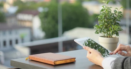 closeup view woman using modern digital tablet computer sitting stylish interior flower diary table blurred city background vertical screen orientation tapping pointing finger display gadget network