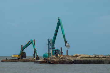 Machines are dredging sand in the sea.