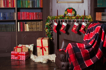 The beautiful interior is decorated for Christmas. Hall, living room, office with a large leather chair, a bookcase with a fireplace. New Year's room with a wreath, a garland, gifts. Place for your te