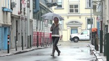 Attractive Woman With An Umbrella Is Walking Out Into A Charming Alley In North Beach San Francisco On A Rainy Day. Checking Her Mobile Phone.