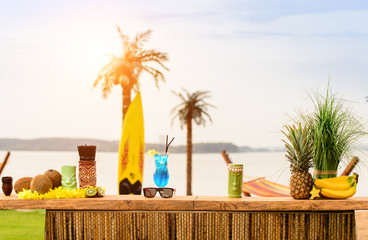 Bar counter on the beach at Hawaii. Glasses with cocktails, coconut, sun glasses lie on the table. Concept of relaxing, preparation and summer