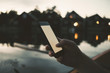 © Maskot - Cropped image of man text messaging through smart phone at lake
