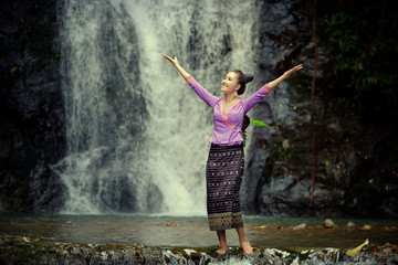 Wall Mural - Laos Woman wearing Laos traditional dress enjoy with nature portrait concept, at the waterfall.