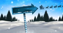 Wooden Signpost In Christmas Winter Landscape And Santa's Sleigh