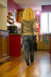 © PhotoAlto - Woman walking toward kitchen at home, rear view