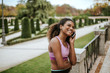 Portrait of young smiling woman wearing sportswear talking on phone outdoors.