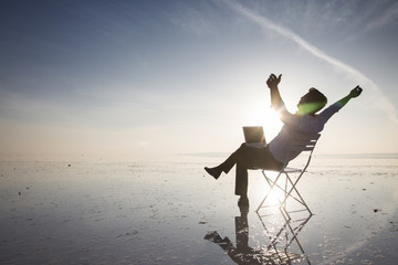 Business man with laptop working on the beach