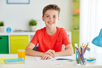 Wall Mural - happy student boy writing to notebook at home