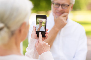 Poster - old woman photographing man by smartphone in park