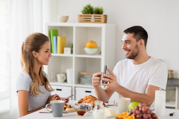 Poster - couple with smartphones having breakfast at home