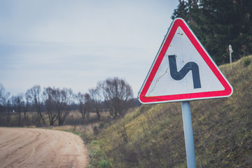 Sharp turn with warning sign on a gravel road.