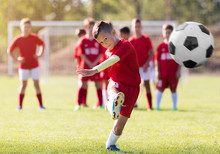Boy Kicking Football On The Sports Field