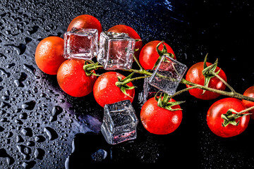 Wall Mural - Banch of red cherry tomatos and ice cubes on black wet table. Selective focus. Toned