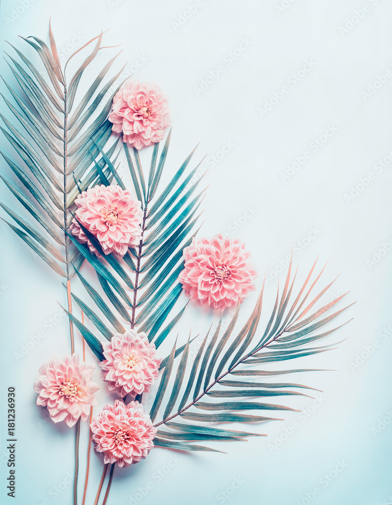Creative layout with tropical palm leaves and pastel pink flowers on