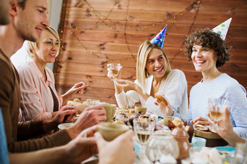 Wall Mural - One of happy girls telling something curious to her friends by birthday table