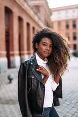 Wall Mural - Portrait of attractive young woman in black leather jacket looking at camera.