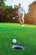 © Panya Studio - Golfer putting golf ball on the green golf.