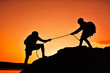 © sawitreelyaon - Silhouette of girl helping man teamwork success on top mountain during sky sunset