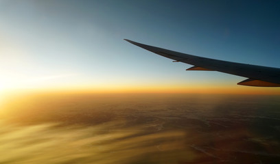 Wall Mural - golden sunlight spreading on aerial cloud below airplane wing