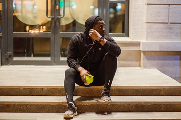 young man sitting on the ground at night, runner in break