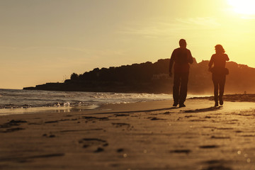 Silhouette of couple walking on the beach at sunset