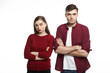 Annoyed young man and woman facing relationships problems, having conflict or quarrel, not speaking to each other, posing in studio with arms crossed. Angry parents being mad at their mischievous son