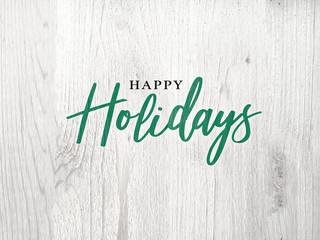 Wall Mural - festive happy holidays calligraphy text over white rustic wood background
