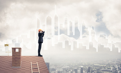 Engineer man standing on roof and looking in binoculars. Mixed m