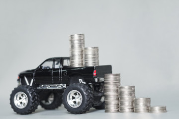 Miniature car pickup truck with stacks of coins on grey background with copy space, banking savings money and business finance concept.