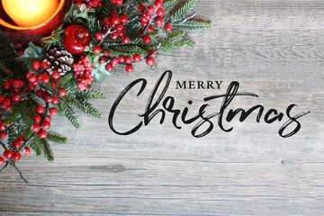 Wall Mural - merry christmas text, festive holiday candle, pine tree branches and berries in top corner over rust