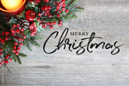 Fotografie, Obraz Merry Christmas Text, Festive Holiday Candle, Pine Tree Branches and Berries in