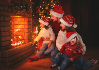 Wall Mural - happy family sitting by fireplace on christmas eve