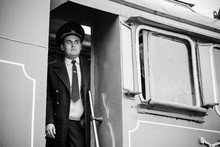 European Or American Train Conductor Is On His Duty On A Platform And Other Trains. Railway, Steam Trains, Vintage Trains