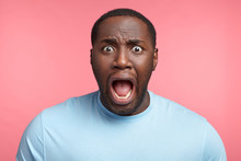 Excited African American Man Screams In Panic, Gaze With Bugged Eyes, Shocked To Hear Bad News. Surprised Male Has Stressful Situation. Great Astonishment, Disbelief, Facial Expressions Concept