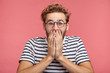 © WHstudio Leushin N - Isolated shot of amazed cheerful stylish guy can`t believe in such happiness, covers mouth with hands. Stylish male giggles, tries to control emotions, watches funny video, isolated on pink background