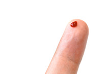 Finger With A Drop Of Blood On An Isolated Background. One Finger With Blood Drop, Isolated On White.