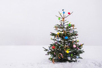 curious open air christmas tree in the snow decorated with sausages, balloons, toilet brushes and cl