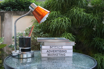 Several textbooks on glass table with table lamp