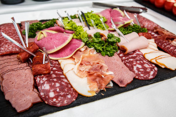 Food tray with delicious salami, pieces of sliced ham, sausage, salad - Meat platter with selection