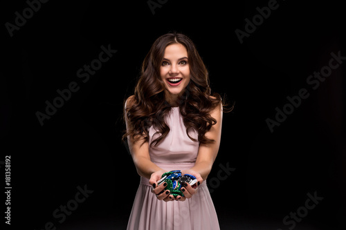 Fotografie, Obraz Female Poker player with paint black nails hold her poker chips to make a bet