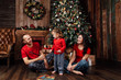 © photominus21 - The family in pajamas plays next to a Christmas tree and a fireplace.