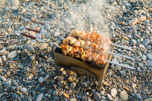 High-angle Shot Of Shashlik Fried On A Mangal On The Pebble Beach

