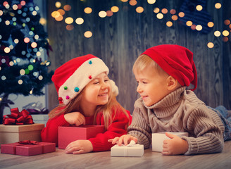 Boy and girl lying on the floor with presents near christmas tree